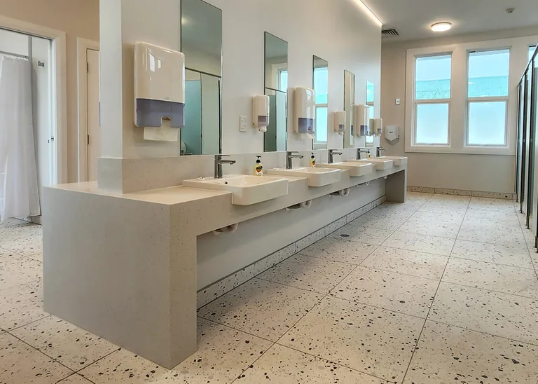 Refurbished hostel bathroom at St Joseph's Māori Girls' College: a long terrazzo vanity with four basins and mirrors above