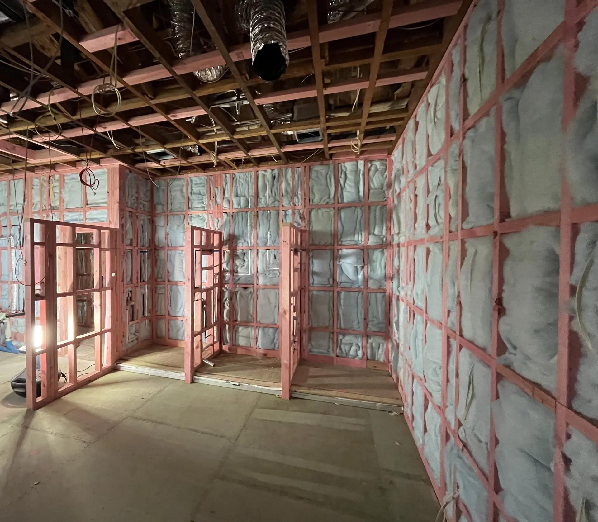 Interior under construction, with timber framing, wall insulation and ceiling services roughed in